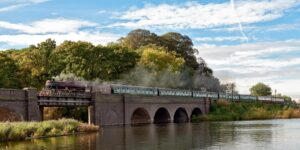 An old steam train going over a bridge