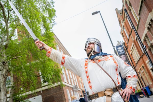 man in roman dress holding sword in air