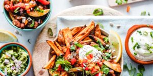 Vegan sweet potato loaded fries in a bowl on a table platter