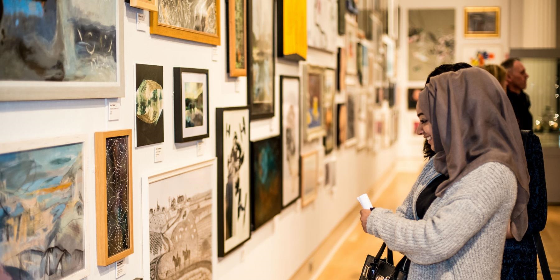 Muslim lady looking at Artwork on the wall