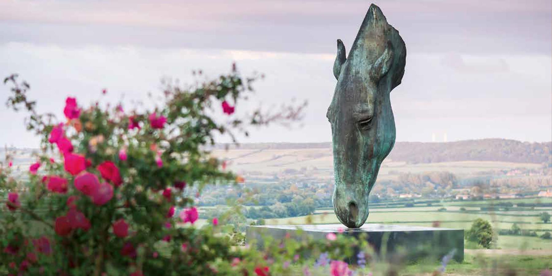 statue of a horses head with fields in the background