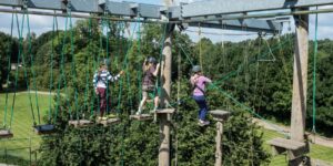 Three young people on High Ropes Course at Leicester Outdoor Pursuits Centre
