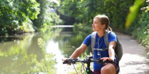A girl on a bike by the side of a river