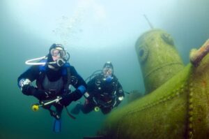 two divers underwater near a submarine wreck