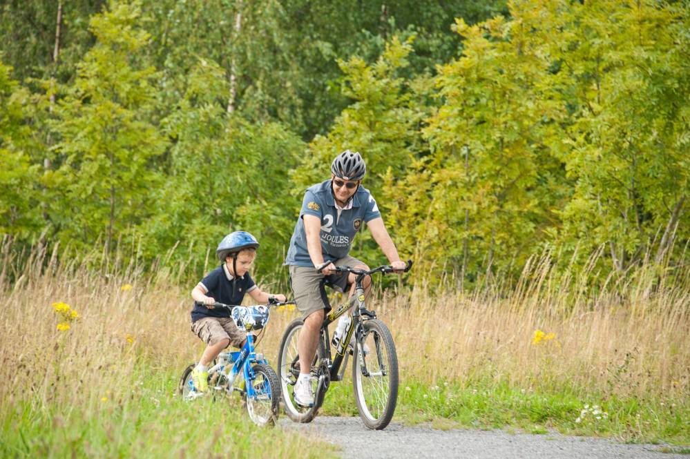 A man and child cycling in woodland