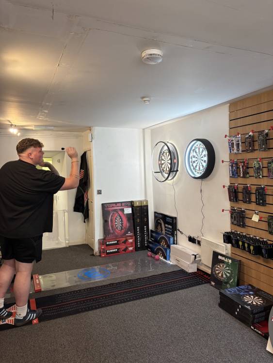 A man throwing darts in a shop