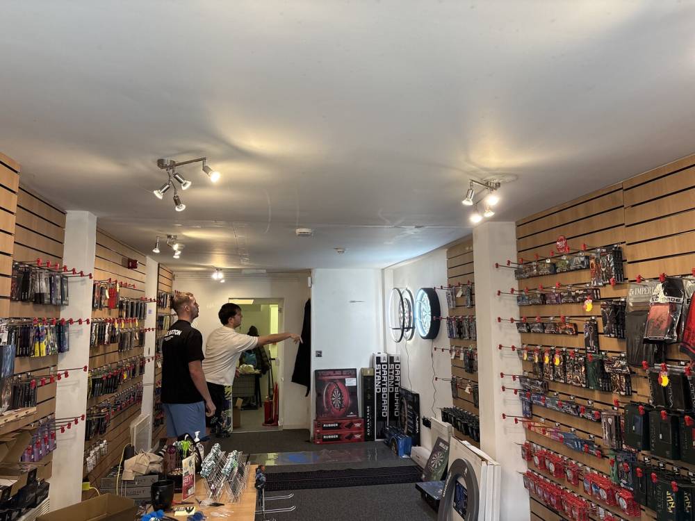 A man throwing darts in a shop