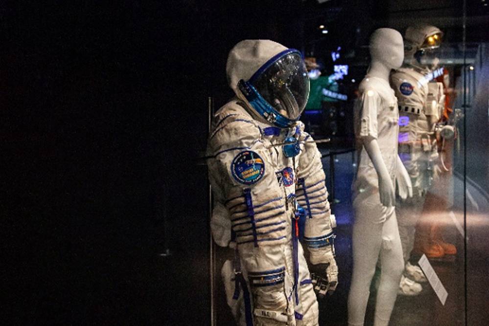 two spacesuits in a display cabinet